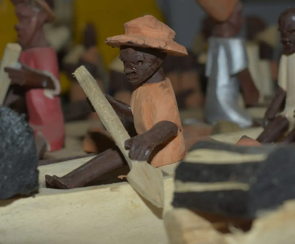 Men carving a wooden canoe together